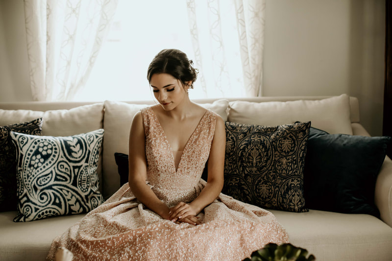 birthday girl in sparkly dress sitting on cream couch with blue pillows