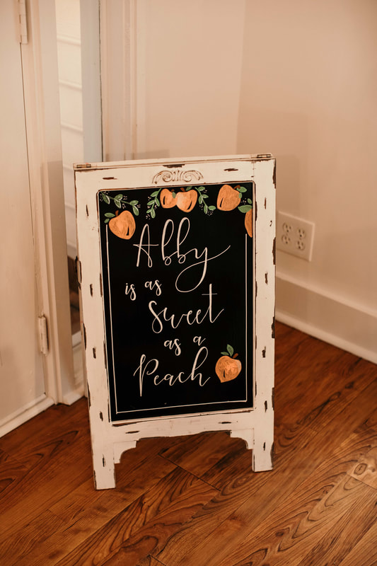 white chalkboard sign says 'abby is as sweet as a peach' with hand drawn peaches