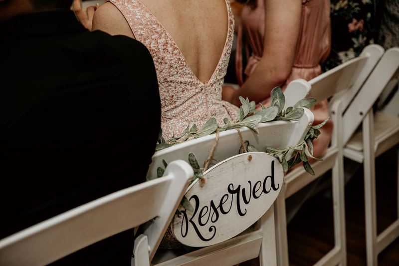 reserved sign on back on white chair with lambs ear greenery