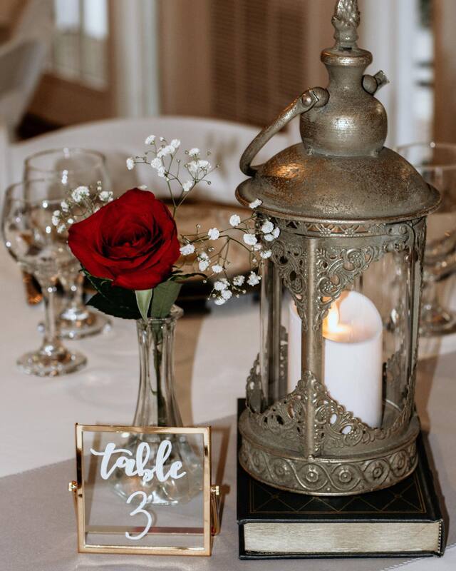 beauty and the beast themed tasting with antique lantern and a rose in a vase with baby's breath