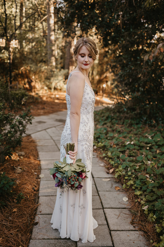 bride in simple, vintage dress holding bouquet while looking down