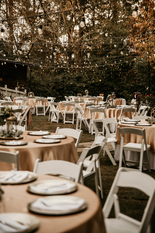 wedding reception area with gold table overlays and white chairs