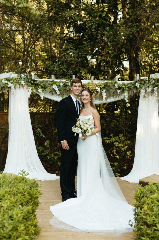 Bride & groom with chiffon, greenery & wisteria altar
