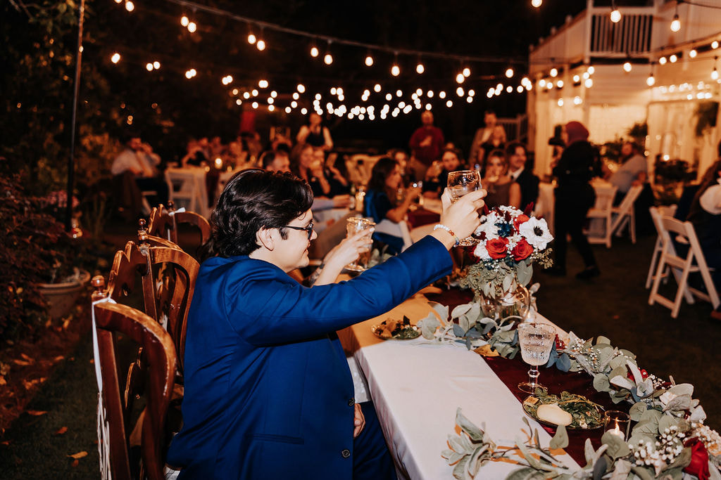 groom toasting glass under edison lights