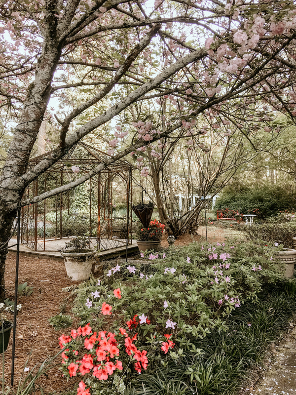 Four Oaks' gazebo surrounded by blooming trees and flower bushes