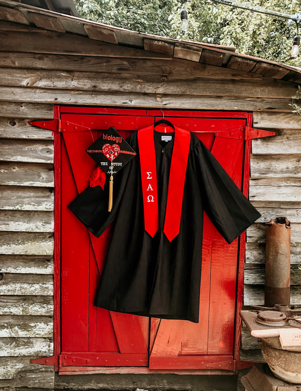 graduation cap and gown by red farm door