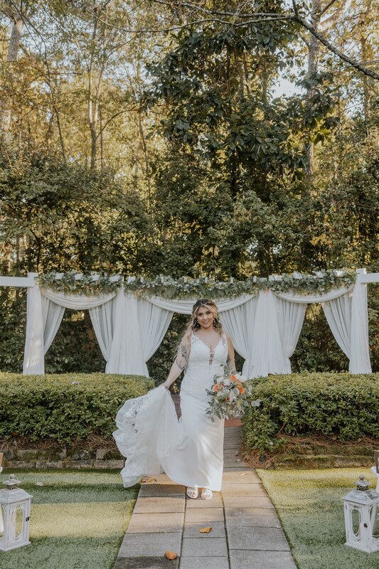 bride in front of garden altar with white drapes and greenery