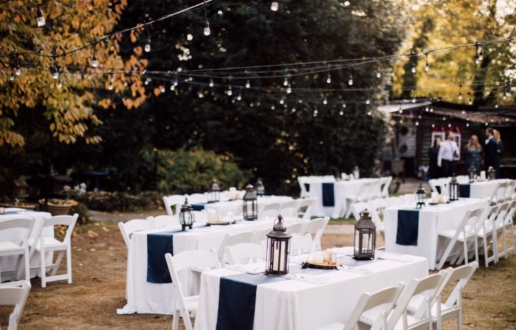 fall outdoor wedding with changing leaves, golden light, string lights, and rectangle guest tables with rustic decor