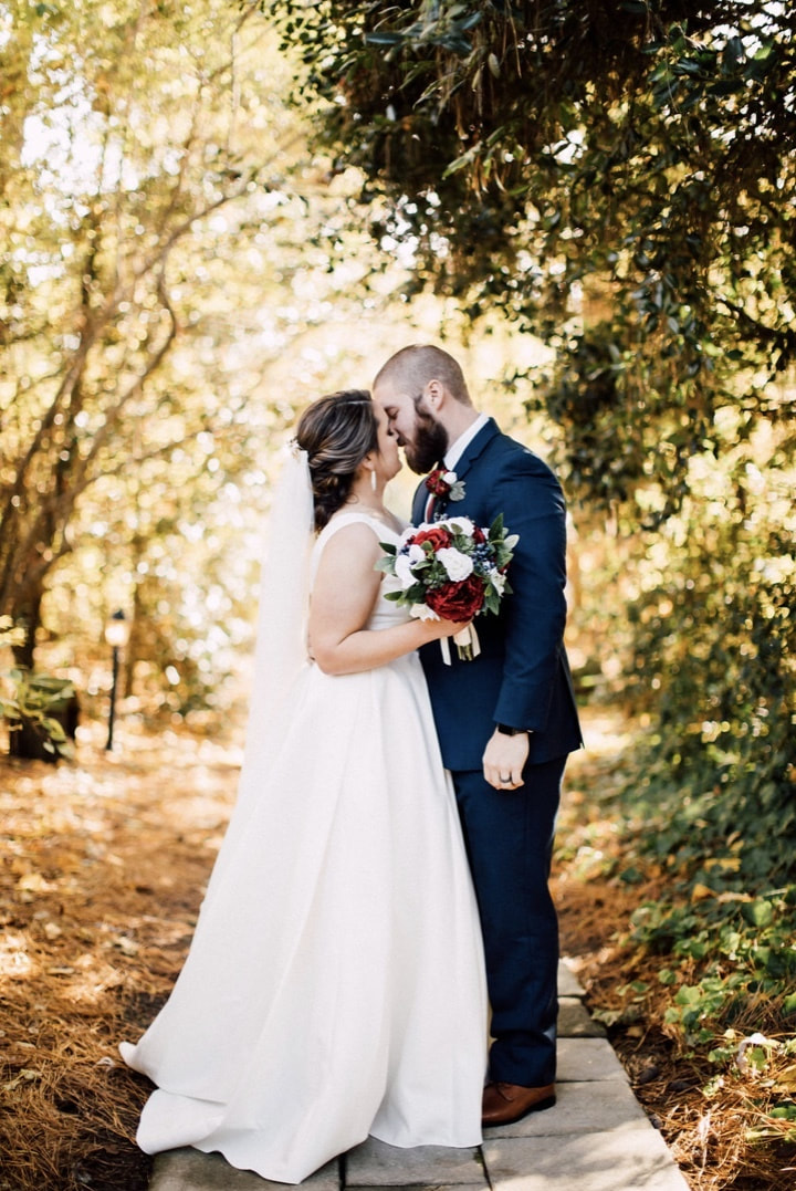 newlyweds almost kissing surrounded by trees with golden light