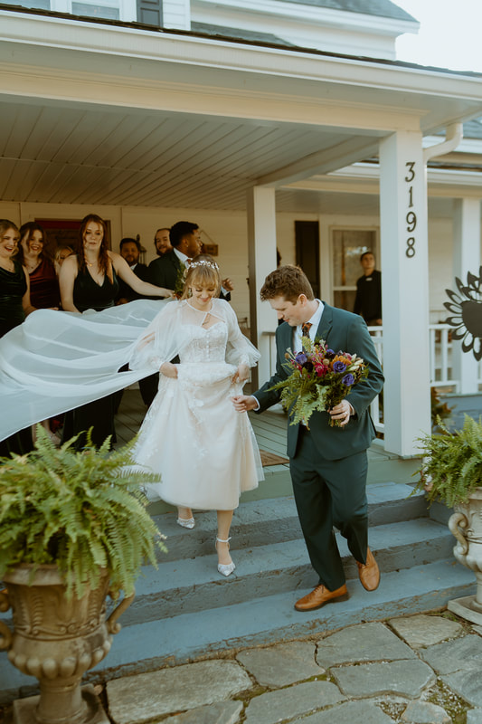 groom and bridesmaids helping vintage bride down farmhouse steps