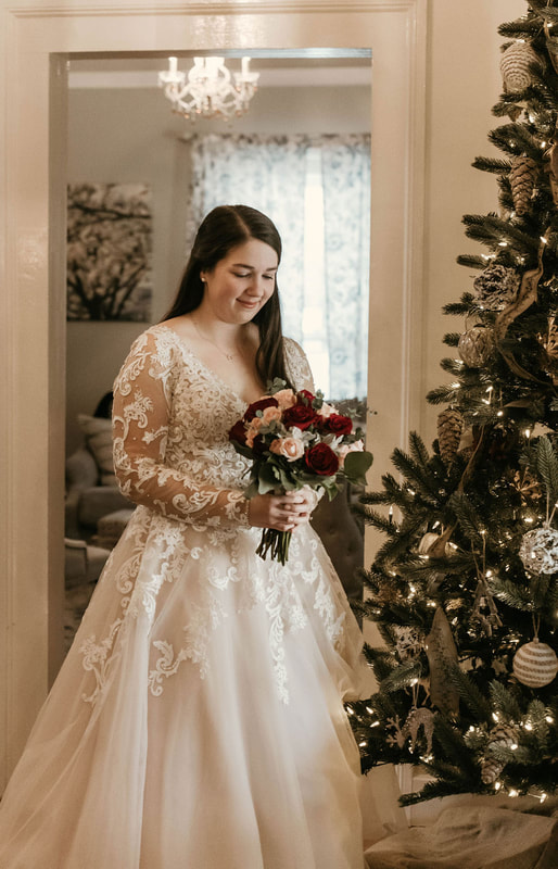 winter bride by Christmas tree holding red and blush bouquet