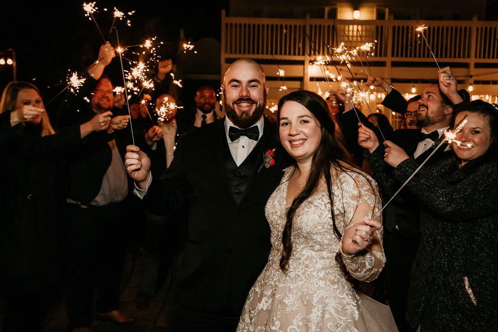 couple holding sparklers with guests for mock grand exit at winter reception