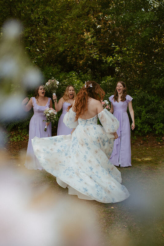 bridesmaids in purple reacting to bride's floral dress