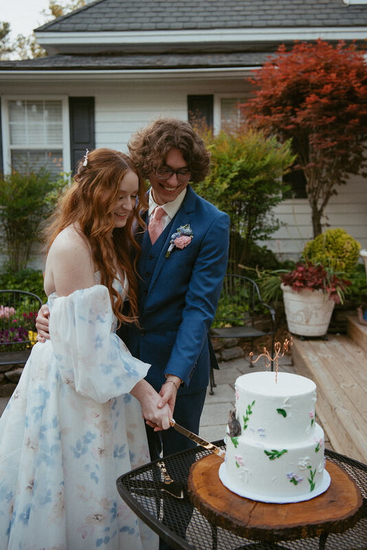 bride and groom cut cake by garden pond