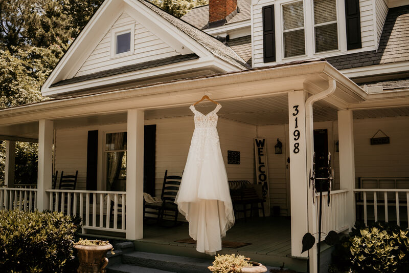 wedding dress hanging on front of white farmhouse