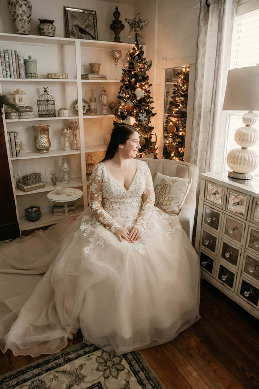 bride with long-sleeved lace dress sitting in farmhouse room decorated for Christmas