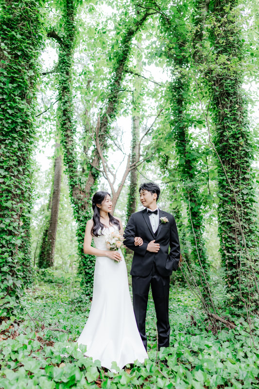 korean bride and groom surrounded by ivy-covered trees